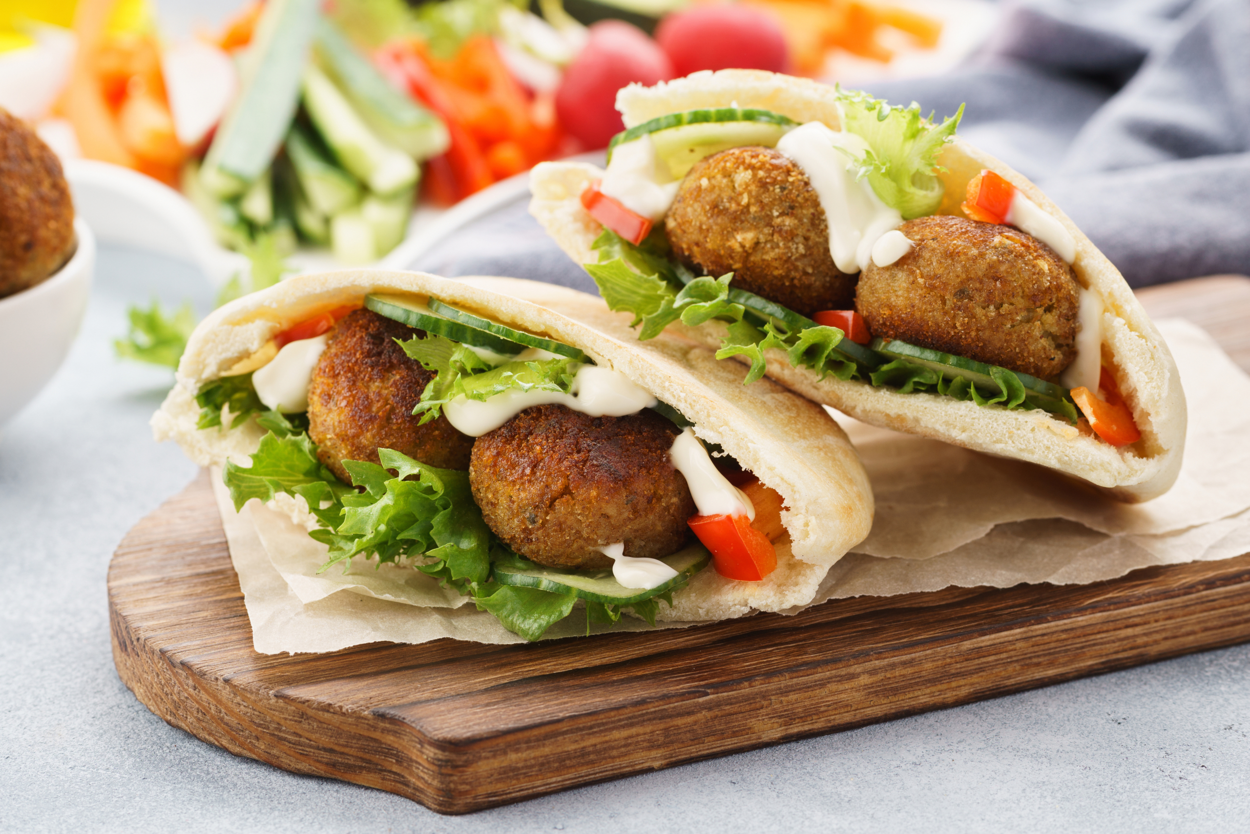 Healthy vegetarian falafel pita with fresh vegetables, lettuce and sauce.